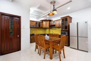 cocina con mesa de madera, sillas y nevera en The Lovenote Home en Ho Chi Minh