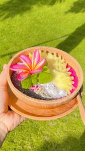 a person holding a flower in a wooden bowl at Ocean Paradise Cottage in Nusa Lembongan