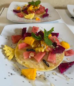 two plates of food with fruit on them at Ocean Paradise Cottage in Nusa Lembongan