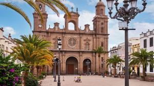 Una vieja iglesia con palmeras delante. en Casa Andrea en Las Palmas de Gran Canaria