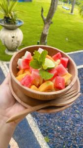 a person holding a bowl of watermelon and fruit at Ocean Paradise Cottage in Nusa Lembongan