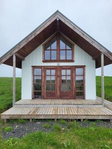 une petite maison avec une terrasse en bois dans un champ dans l'établissement Hólar Countryside Cabin 2, à Selfoss