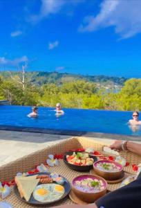 a table with food and people in a swimming pool at Ocean Paradise Cottage in Nusa Lembongan