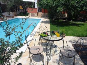 - une table et des chaises à côté de la piscine dans l'établissement Apartment Kućica, à Zadar
