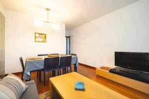 a living room with a table with chairs and a tv at Piles Garden Apartamento in Gijón