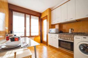 kuchnia z białymi szafkami i zmywarką do naczyń w obiekcie Piles Garden Apartamento w mieście Gijón