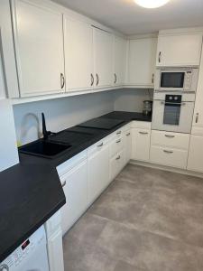 uma cozinha com armários brancos e um balcão preto em Charmante Ferienwohnung mit Klimaanlage ! em Mainaschaff