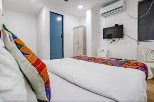 a bedroom with a bed and a tv on a wall at FabExpress VYS Inn in Pune