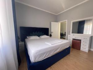 a bedroom with a large bed with a blue headboard at LuxuryApt/KingBed/Bathtub/HomeOffice/53inchSmartTv in Tirana