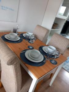 a wooden table with plates and wine glasses on it at NEW TO MARKET - Spectre Home, Hatfield - Contractors, Engineers, Relocators, LongStay Discounts, Parking in Hatfield