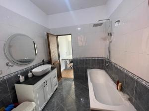 a bathroom with a tub and a sink and a mirror at LuxuryApt/KingBed/Bathtub/HomeOffice/53inchSmartTv in Tirana