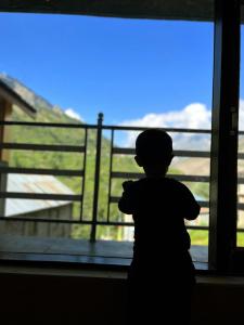 Un ragazzo in piedi davanti a una finestra di Amma Home Stay Keylong a Kyelang