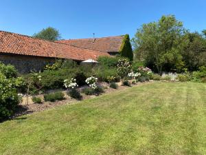 a garden with flowers and plants in front of a house at Barnacle Barn, North Norfolk in Roughton