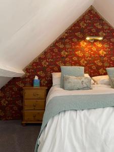 a bedroom with two beds and a wall with flowers at Barnacle Barn, North Norfolk in Roughton