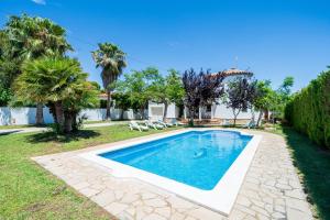 a swimming pool in a yard with palm trees at Vila Tres Cales in Les tres Cales
