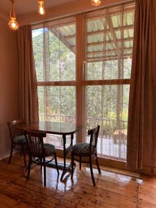 ein Esszimmer mit einem Tisch und Stühlen sowie einem großen Fenster in der Unterkunft MELQONYAN'S Guest House & Coffee in Tʼumanyan