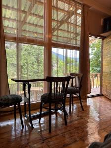 einen Tisch und Stühle in einem Zimmer mit einem großen Fenster in der Unterkunft MELQONYAN'S Guest House & Coffee in Tʼumanyan