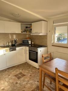 a kitchen with white cabinets and a wooden table and a table and a tableearcher at Apartment Gloria 4 NEW in Belgrade