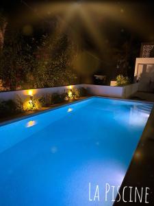 a large blue swimming pool at night with lights at MAISON FLORAL in Saly Portudal