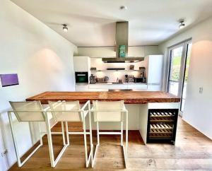 cocina con encimera de madera y sillas blancas en Traumhaus Baldeneysee en Essen