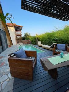 un patio con piscina, mesa y sillas en Unique wooden villa with pool en Olympiada