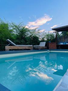 una piscina de agua azul y un banco en Unique wooden villa with pool, en Olympiada