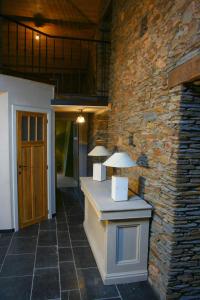 Habitación con pared de piedra y mesa con 2 lámparas. en La ferme Claudlisse, en Vielsalm