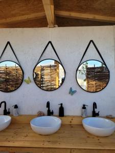 three sinks in a bathroom with two mirrors at Makeeda Camping in Vama Veche