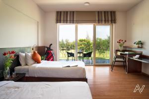 a hotel room with two beds and a desk and a balcony at Clover Greens Golf Course & Resort - Attibele, Hosur in Sarjāpur