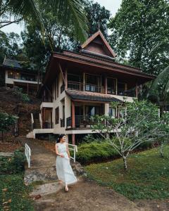 a woman in a white dress standing in front of a house at Kooncharaburi Resort - Koh Chang in Ko Chang