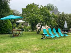 a group of chairs and tables and an umbrella at Chambre studio familiale la Brandonnière in Courson
