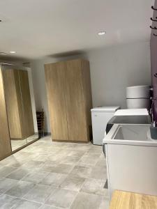 a kitchen with wooden cabinets and a tile floor at Appartement cosy à la campagne in Languidic +4 photos