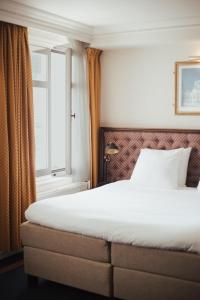 Ce lit se trouve dans une chambre d'hôtel dotée d'une fenêtre. dans l'établissement Boutique Hotel De Doelen, à Groningue