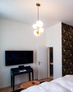1 dormitorio con 1 cama, TV y mesa en Grâce Boutique Apartments, en Halle an der Saale
