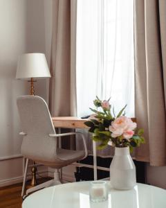 un jarrón de flores sentado en una mesa junto a una ventana en Grâce Boutique Apartments, en Halle an der Saale