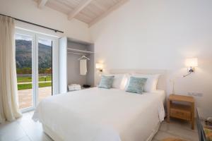 a white bedroom with a bed and a large window at Avraam Sunset Villas with Private Heated Pools by Imagine Lefkada in Kalamitsi