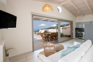 a living room with a white couch and a television at Avraam Sunset Villas with Private Heated Pools by Imagine Lefkada in Kalamitsi
