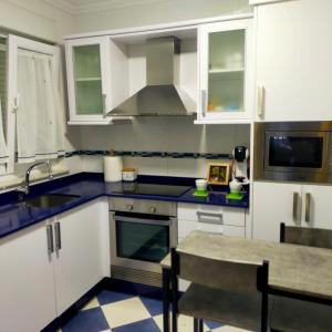 a kitchen with white cabinets and a sink and a table at Rocas Brancas in Ribadeo