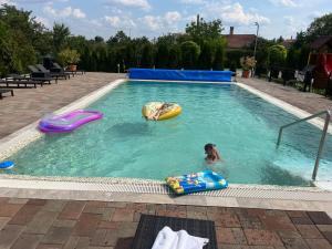 a person swimming in a swimming pool with inflatables at Meggyes Hotel in Szerencs