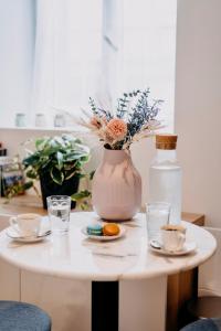 - une table blanche avec un vase, 2 tasses et des boissons dans l'établissement Bel écrin sur l'île de Nantes - GARE TGV, CHU, CONGRES, à Nantes