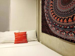 uma cama com uma almofada vermelha e uma tapeçaria em 4 Bedroom Villa near Clark (Casa Isabela) em Mabalacat