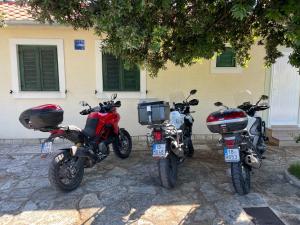 drie motorfietsen geparkeerd voor een gebouw bij Apartments Antonija Punta Skala next to Falkensteiner Resort in Petrcane