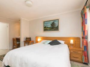 um quarto com uma grande cama branca e uma secretária em Parkhurst Cottage em Joanesburgo