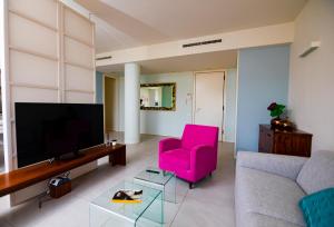 a living room with a pink chair and a tv at Prime blue suite - Giardini in Riccione