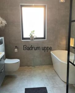 bagno con vasca, servizi igienici e finestra di Stor modern villa med toppläge! a Kalmar