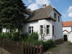 a white house with a wooden fence at Die große Wohnung in Droyßig