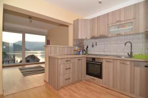 a kitchen with wooden cabinets and a large window at vila sunset in Konjic