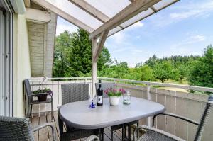 - une table sur un balcon avec une bouteille de vin dans l'établissement Beutenmühle Straussenfarm Dach, à Owingen