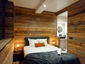a bedroom with a wooden wall with a large bed at Le Enecy - Spa - Cœur Vieille ville in Annecy