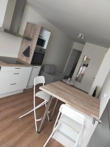 une cuisine avec une table en bois et deux chaises blanches dans l'établissement T2 hyper centre LONS LE SAUNIER, à Lons-le-Saunier